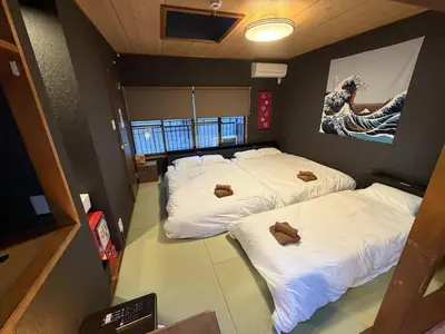 three beds in a room with white sheets at Yama Hotel Tsukiji in Tokyo