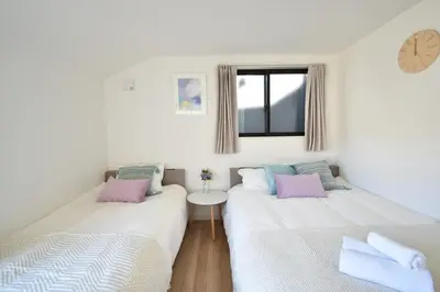 two beds in a room with a clock on the wall at 100sqm 4BDR New House! 6 minutes from Skytree by train in Tokyo
