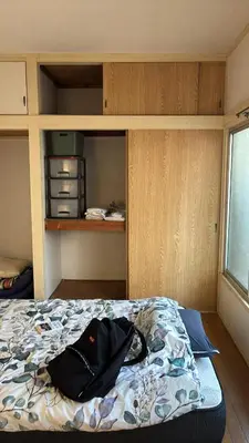a bedroom with a bed with a backpack on it at \u7b2c\u4e00\u30a2\u30d1\u30fc\u30c8 in Tokyo