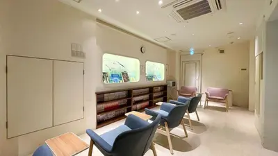 a waiting room with chairs and a book shelf at Spa&Capsule Hotel Grandpark Inn Kitasenju in Tokyo