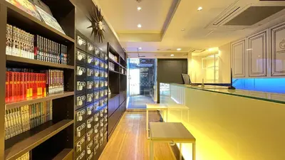 a bar in a library with a desk and bookshelves at Spa&Capsule Hotel Grandpark Inn Kitasenju in Tokyo