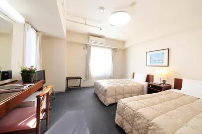 a hotel room with two beds and a desk at Shinjuku Urban Hotel in Tokyo