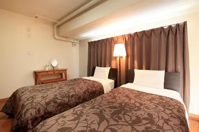 a hotel room with two beds and a window at Shinjuku Urban Hotel in Tokyo