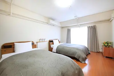 a hotel room with two beds and a window at Shinjuku Urban Hotel in Tokyo