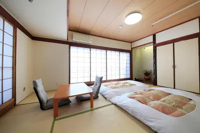 a room with two beds and a table and windows at Shinjuku Urban Hotel in Tokyo