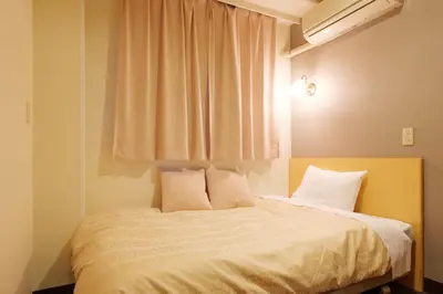 a bedroom with a bed with white sheets and a window at Hotel Suntargas Ueno in Tokyo