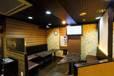a dining room with two tables and a tv at Capsule Land Yushima (Male Only) in Tokyo