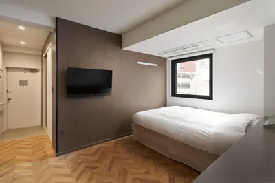 a bedroom with a bed and a flat screen tv at Shinjuku City Hotel N.U.T.S Tokyo in Tokyo