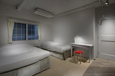 a bedroom with two beds and a red stool at Shinjuku City Hotel N.U.T.S Tokyo in Tokyo