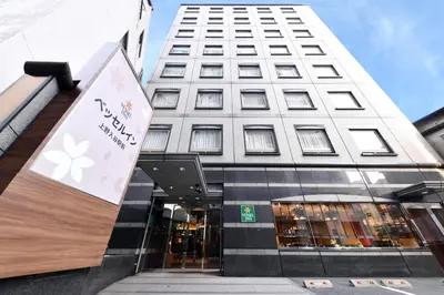 a tall white building with a sign in front of it at Vessel Inn Ueno Iriya Station in Tokyo