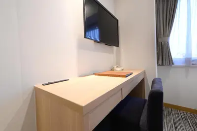 a room with a desk with a tv on a wall at Vessel Inn Ueno Iriya Station in Tokyo
