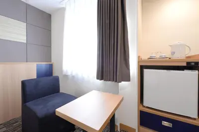 a room with a chair and a table and a window at Vessel Inn Ueno Iriya Station in Tokyo