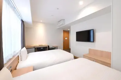 a hotel room with two beds and a tv at Vessel Inn Ueno Iriya Station in Tokyo