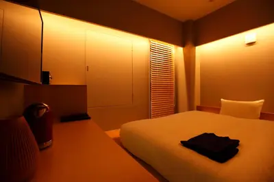 a bedroom with a white bed with a black towel on it at HOTEL AMANEK Ginza East in Tokyo