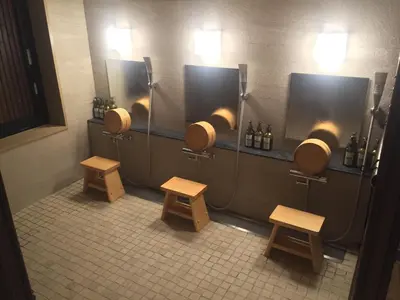 a public bathroom with three urinals and benches in it at NADESHIKO HOTEL TOKYO Shibuya by unito Female-only in Tokyo