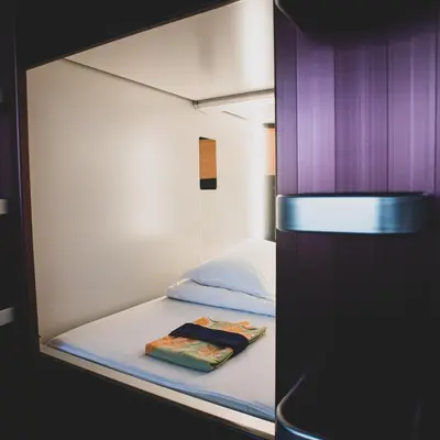 a small bed in a small room with purple walls at NADESHIKO HOTEL TOKYO Shibuya by unito Female-only in Tokyo