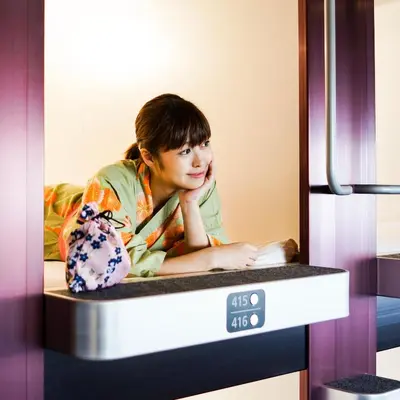 a young girl is sitting on a bed in a machine at NADESHIKO HOTEL TOKYO Shibuya by unito Female-only in Tokyo