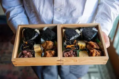 a person holding two wooden boxes filled with food at Araiya Tokyo -Private Townhouse- in Tokyo