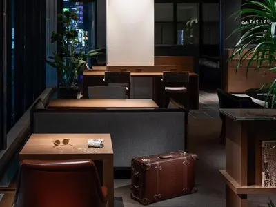 a waiting room with a suitcase and tables and chairs at Mitsui Garden Hotel Kyobashi - Tokyo Station in Tokyo