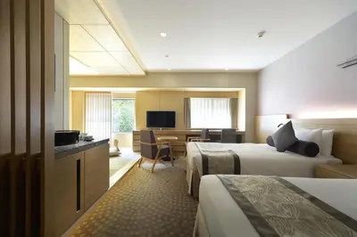 a hotel room with two beds and a desk at Hotel Metropolitan Tokyo Ikebukuro in Tokyo