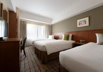 a hotel room with two beds and a television at Hotel Metropolitan Tokyo Ikebukuro in Tokyo