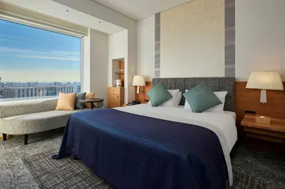 a hotel room with a bed and a couch and a window at Park Hotel Tokyo in Tokyo
