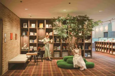 two women sitting in a library with a book shelf at Shiba Park Hotel in Tokyo