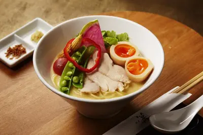 a bowl of soup with chicken and vegetables on a table at Shangri-La Tokyo in Tokyo