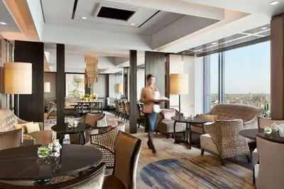 a man walking through a restaurant with tables and chairs at Shangri-La Tokyo in Tokyo