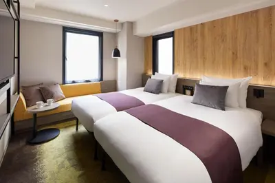 a hotel room with two beds and a couch at the b ochanomizu in Tokyo
