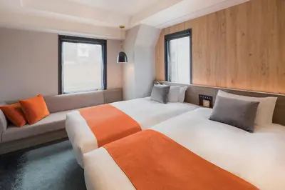 a hotel room with two beds and a couch at the b ochanomizu in Tokyo
