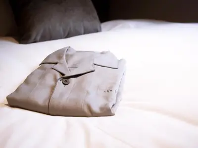 a brown jacket sitting on top of a white bed at the b ochanomizu in Tokyo