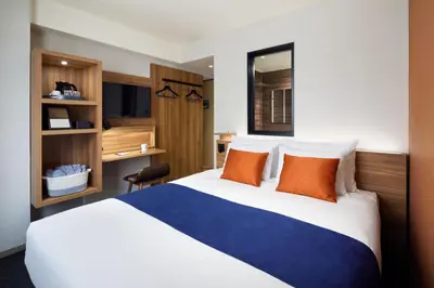 a hotel room with a large bed with orange pillows at the b akasaka-mitsuke in Tokyo