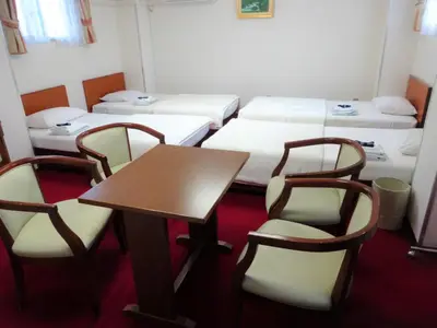 a room with three beds and a table and chairs at Hotel Yanagibashi in Tokyo