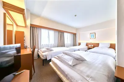 a hotel room with three beds and a window at Daiichi Inn Ikebukuro in Tokyo