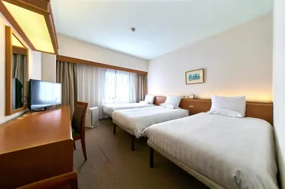a hotel room with two beds and a flat screen tv at Daiichi Inn Ikebukuro in Tokyo