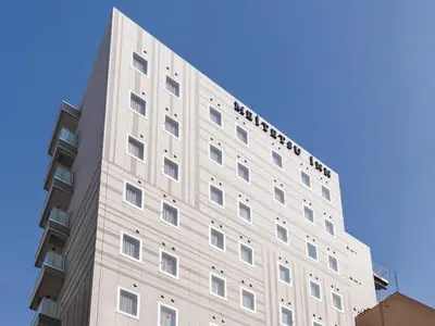 a tall white building with a blue sky in the background at Meitetsu Inn Hamamatsucho in Tokyo