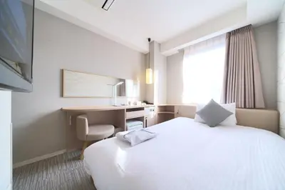 a hotel room with a large white bed and a desk at Meitetsu Inn Hamamatsucho in Tokyo