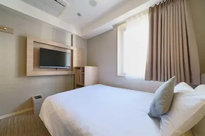 a hotel room with a bed and a flat screen tv at Meitetsu Inn Hamamatsucho in Tokyo