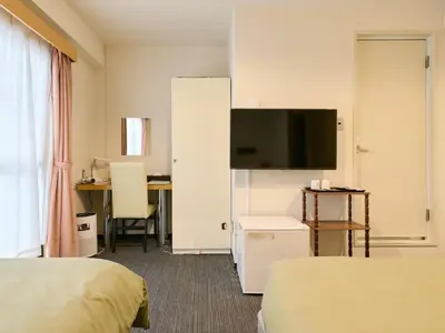 a hotel room with two beds and a flat screen tv at Tabist Hotel Tetora Ikebukuro in Tokyo