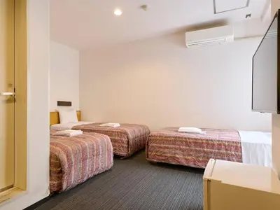 a hotel room with two beds and a tv at Tabist Hotel Tetora Ikebukuro in Tokyo
