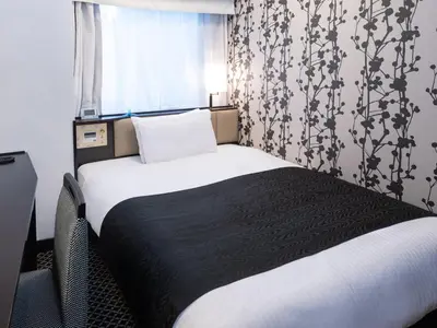 a bedroom with a bed with a black blanket and a window at APA Hotel Ochanomizu Ekikita in Tokyo