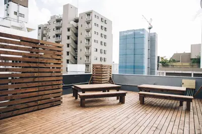 two benches on a rooftop with buildings in the background at Nui. HOSTEL & BAR LOUNGE in Tokyo