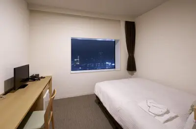 a hotel room with a bed and a desk and a window at Hotel Crown Hills Ueno Premier in Tokyo