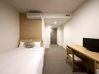 a room with a bed and a desk with a computer at Hotel Crown Hills Ueno Premier in Tokyo