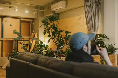 a man sitting on a couch in a room with plants at DENCHI TOKYO - Private Designer Stay in Asakusa in Tokyo