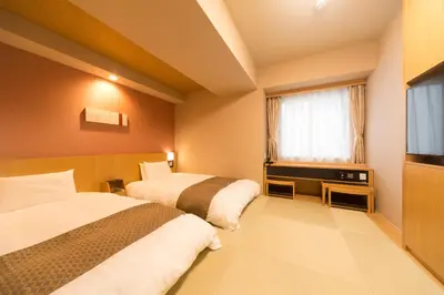 a hotel room with two beds and a flat screen tv at Dormy Inn Premium Tokyo Kodenmacho in Tokyo