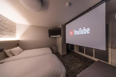 a hotel room with two beds and a large screen at Hotel Cerezo in Tokyo