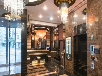a lobby of a building with a staircase and chandeliers at APA Hotel Ginza Shintomicho Ekimae Kita in Tokyo