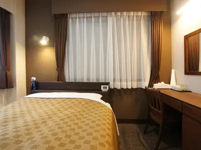 a bedroom with a bed and a desk and a window at Hotel Trend Asakusa in Tokyo